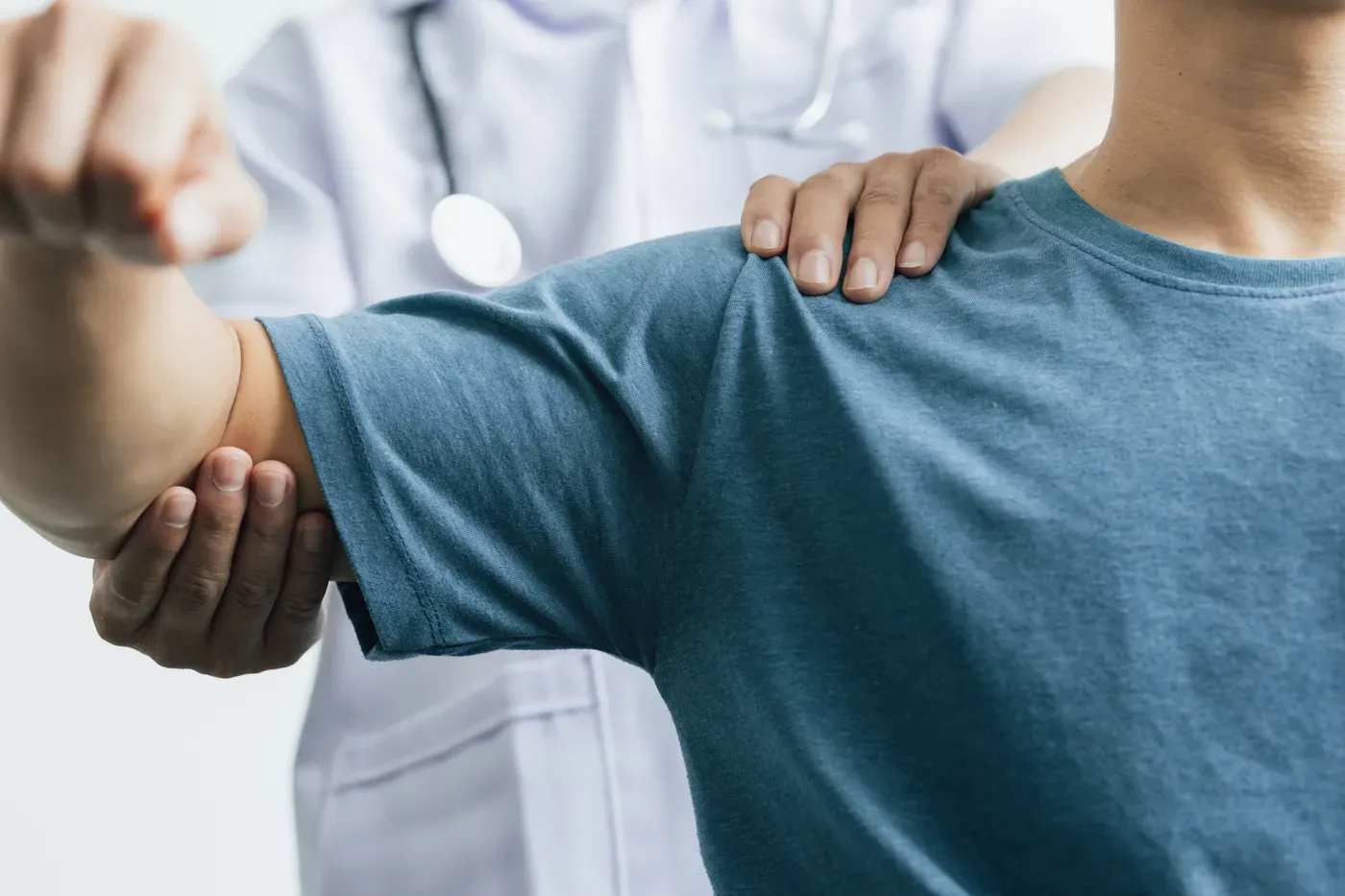 Doctor examining a man’s shoulder and elbow in a clinic