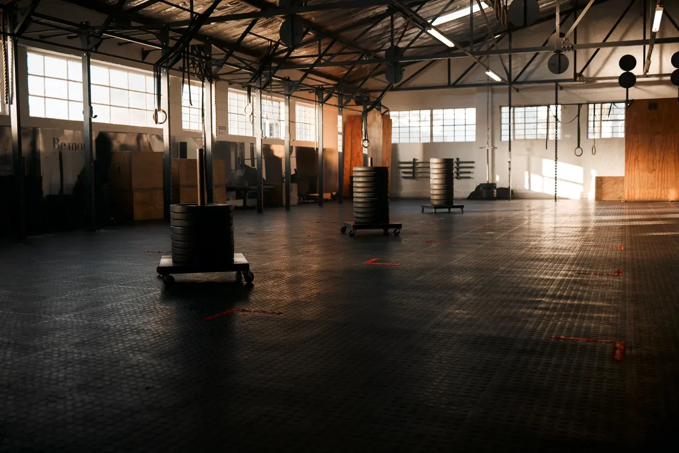 Empty warehouse-style gym with rubber floor, weight plates and rings