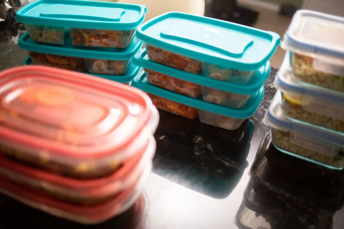 Stacks of plastic meal prep containers filled with cooked food