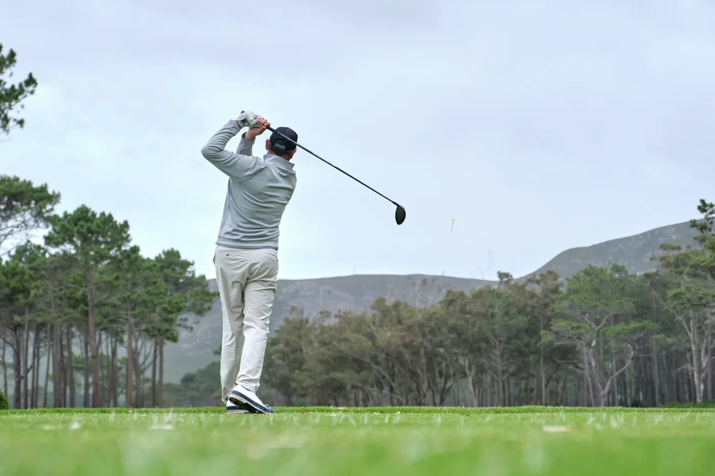 Golfer finishing a full swing with a driver on a tee box
