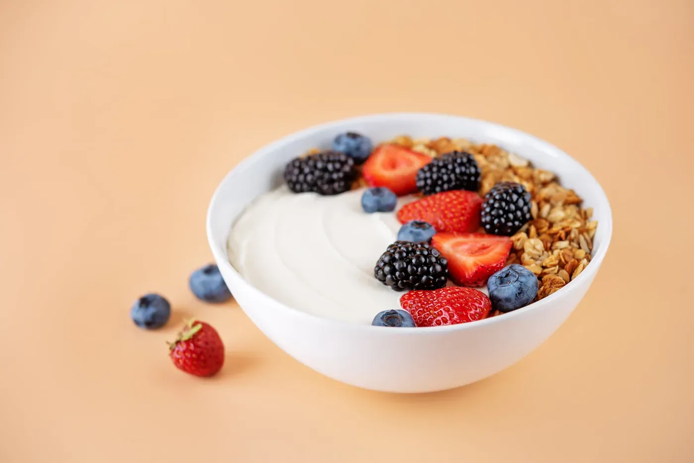 Bowl of Greek yogurt topped with granola, strawberries and blackberries