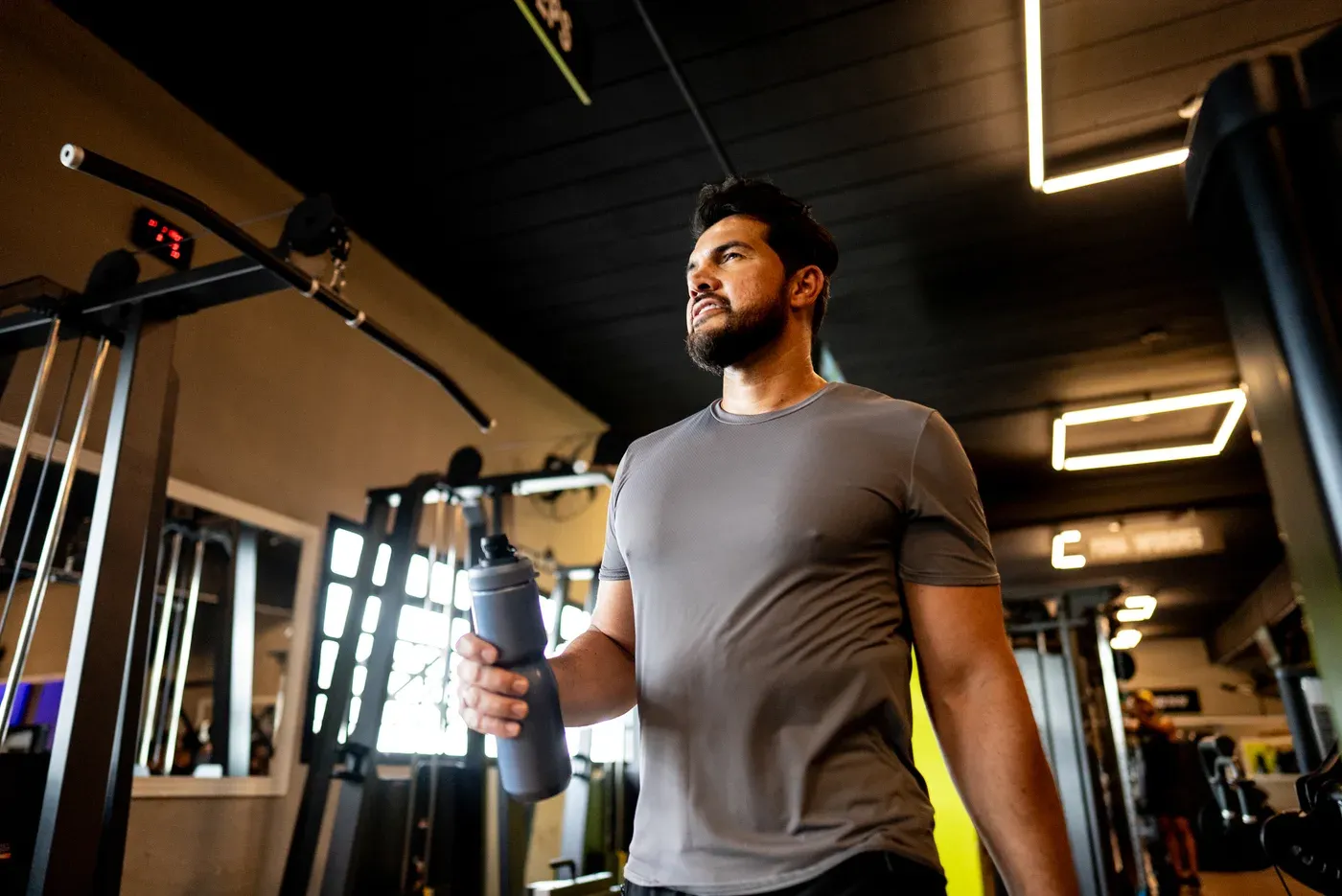Bearded man holding a water bottle as he walks into a gym
