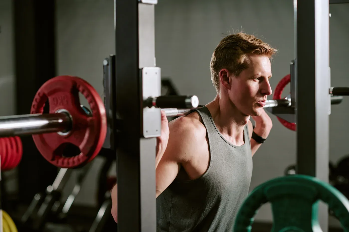 Man under a barbell in a squat rack getting ready to squat