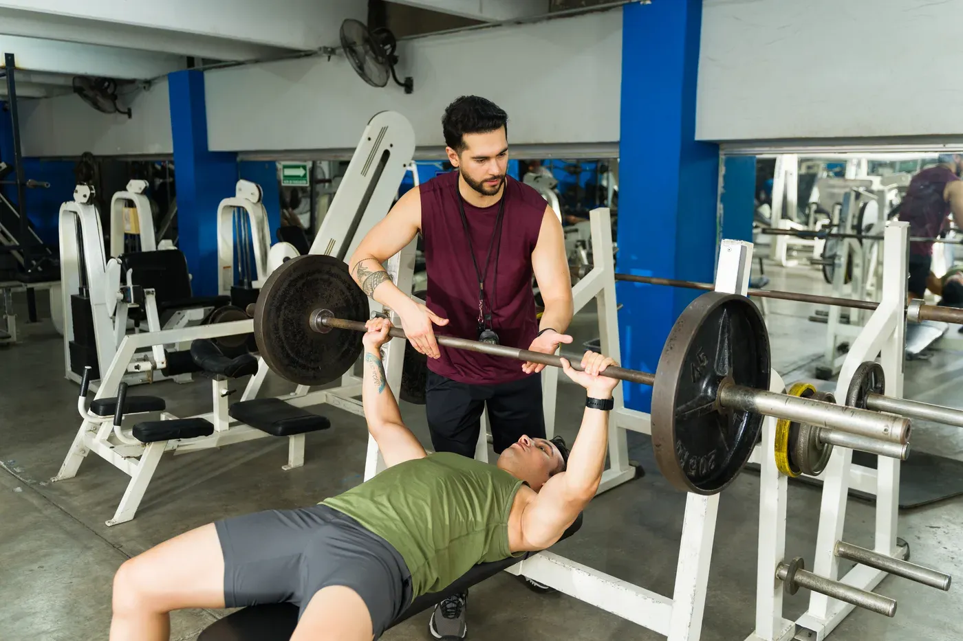 Personal trainer spotting a man doing a barbell bench press