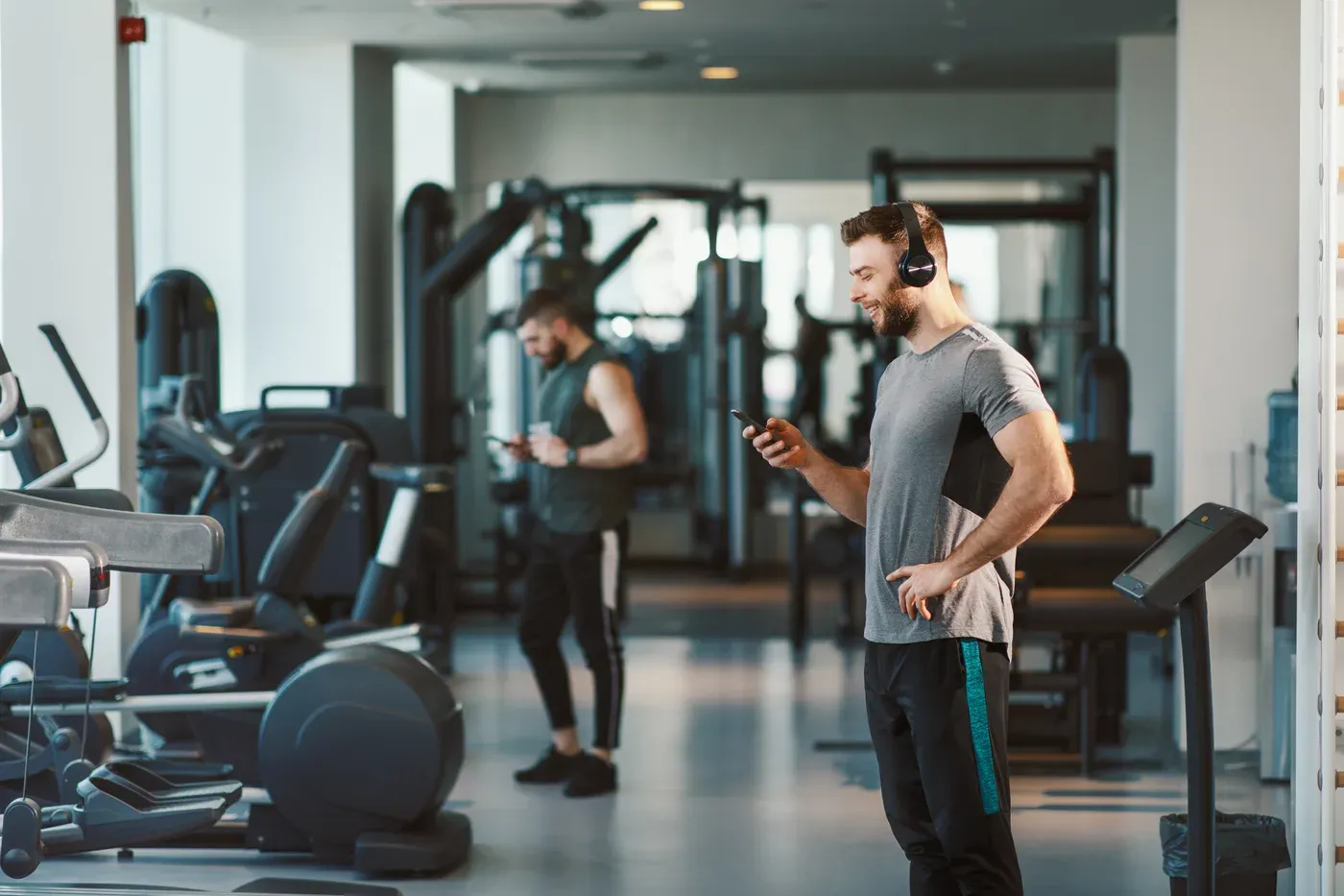 Man in headphones choosing music on his phone in a gym