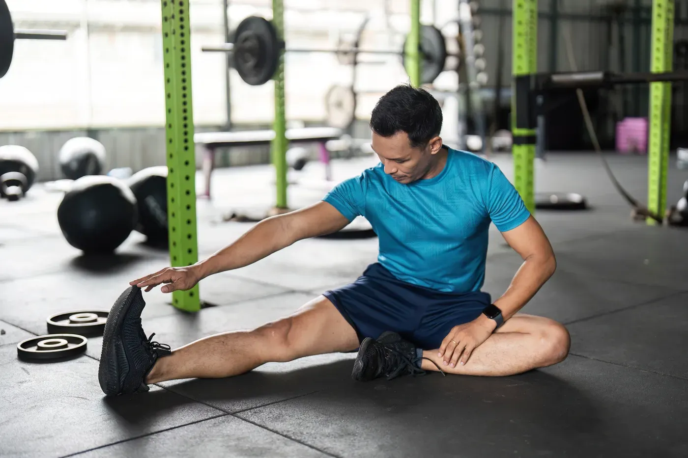 Man doing a seated hamstring stretch on a gym floor