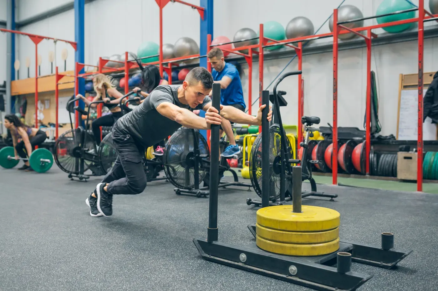 Man pushing a loaded sled across a gym floor