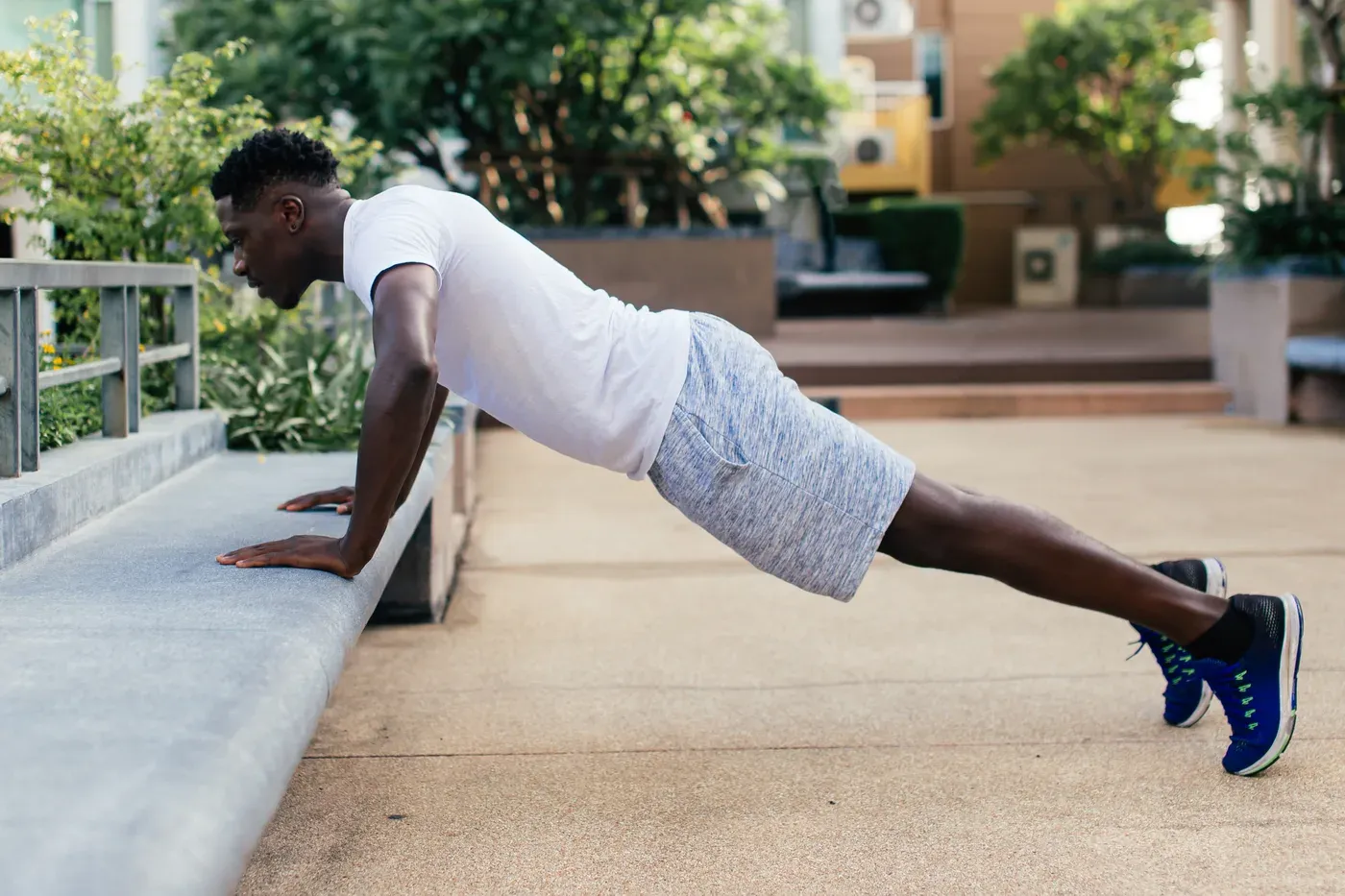 Man doing incline push-ups on a concrete ledge outdoors