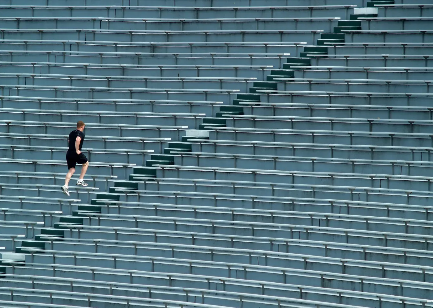 Man running up stadium bleacher steps seen from a distance