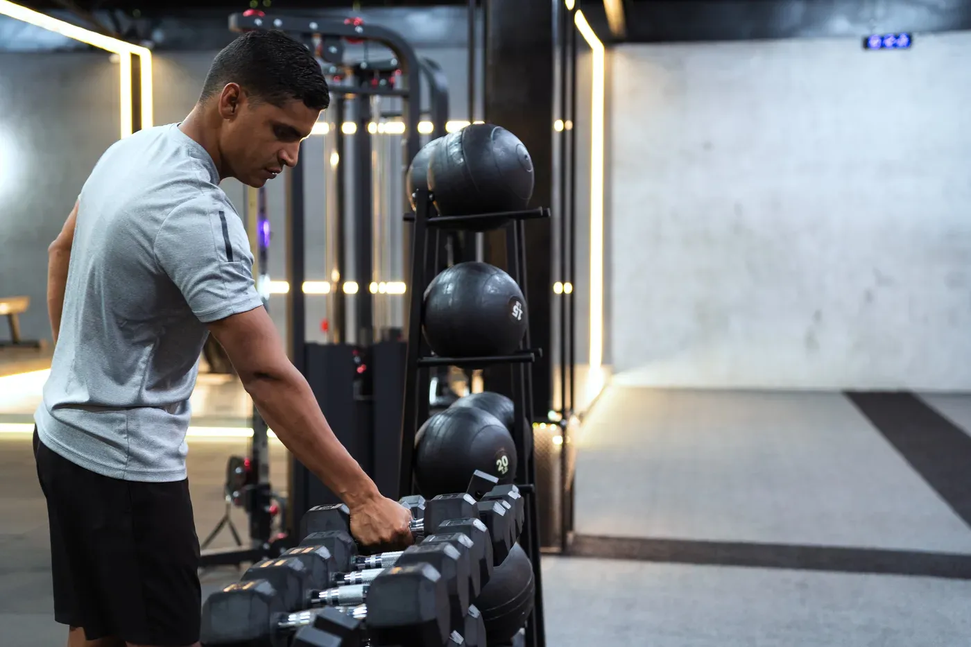Man choosing a dumbbell from a rack in a modern gym