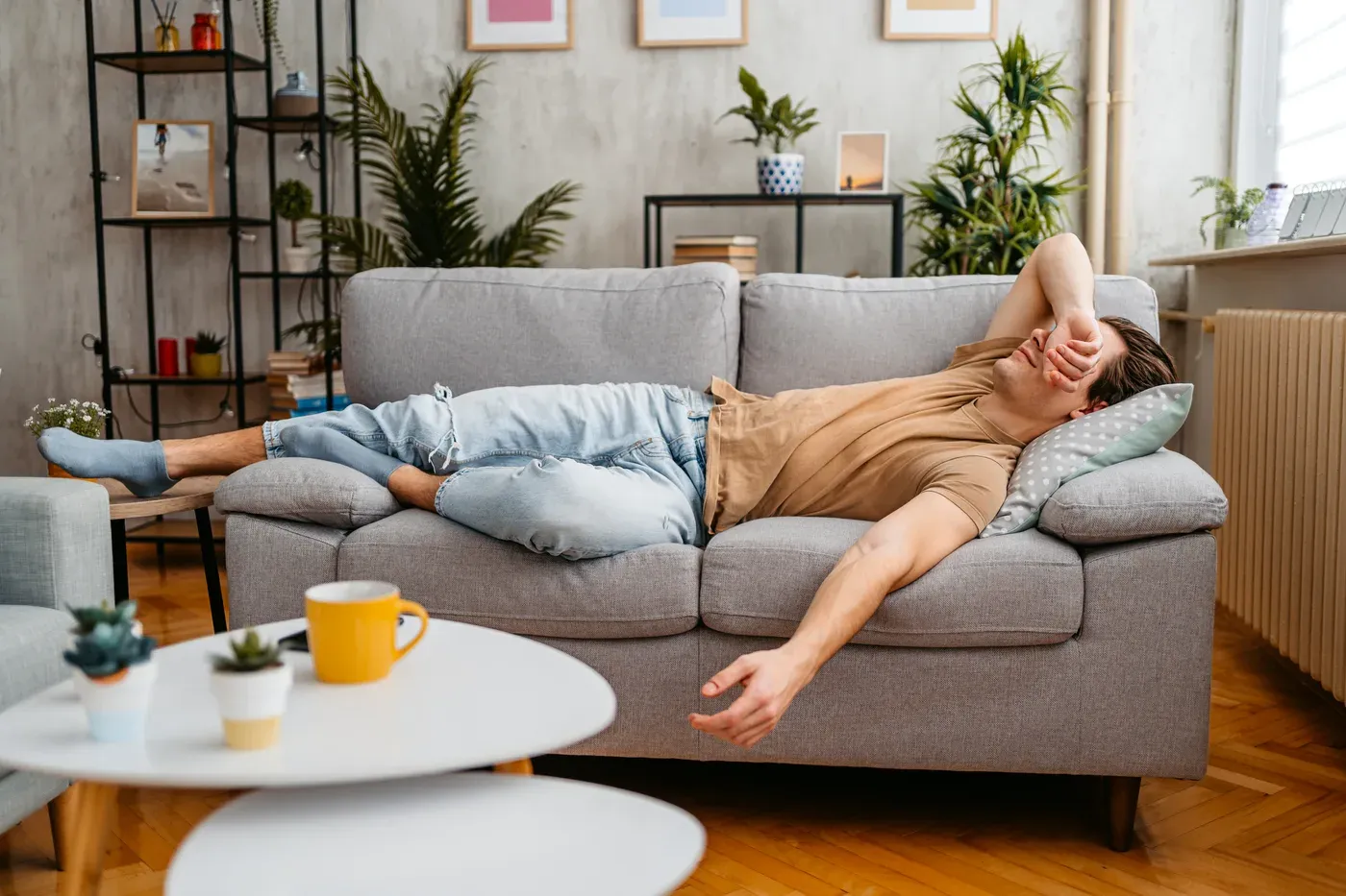 Tired man lying on a sofa with his arm over his face