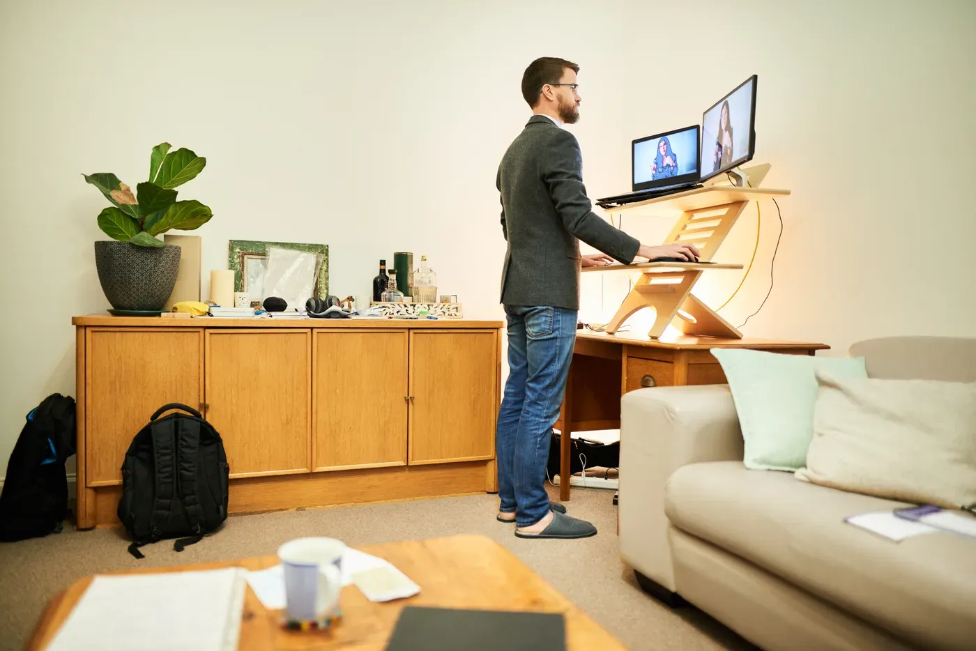 Man in a blazer working at a standing desk in his living room