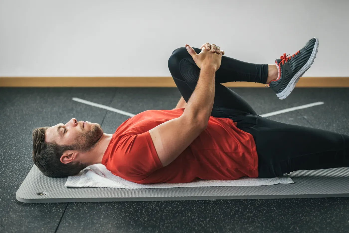 Man lying on a mat pulling one knee to his chest