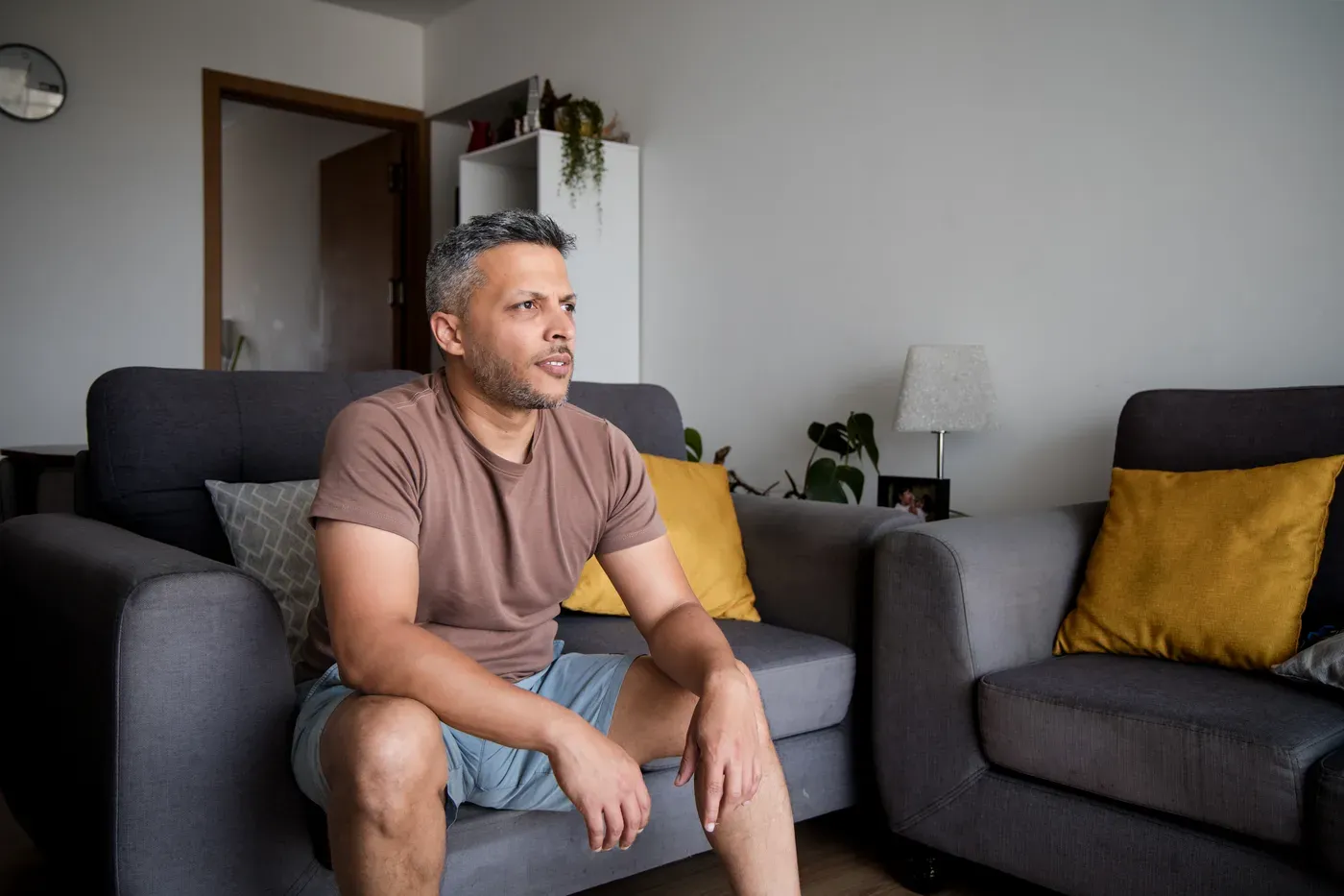 Grey-haired man in a T-shirt and shorts sitting on a sofa