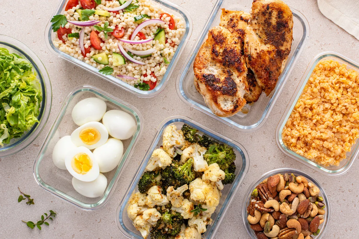 Glass meal prep containers with grilled chicken, boiled eggs, vegetables and nuts