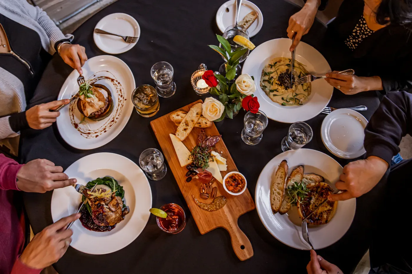 Overhead view of a restaurant table with plated dinners and shared appetizers