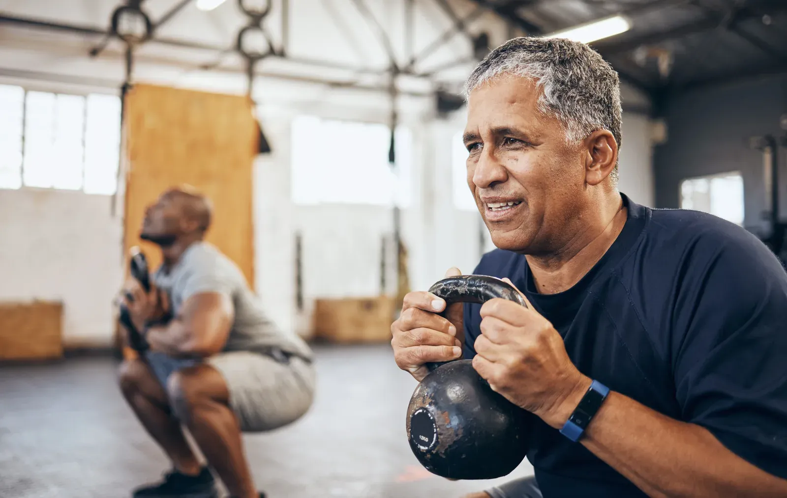 Man in his fifties training with a kettlebell alongside his coach