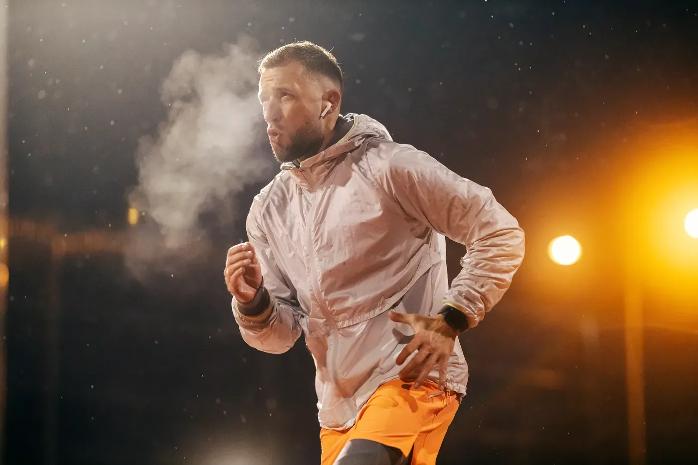 Man running at night in winter with his breath visible under streetlights