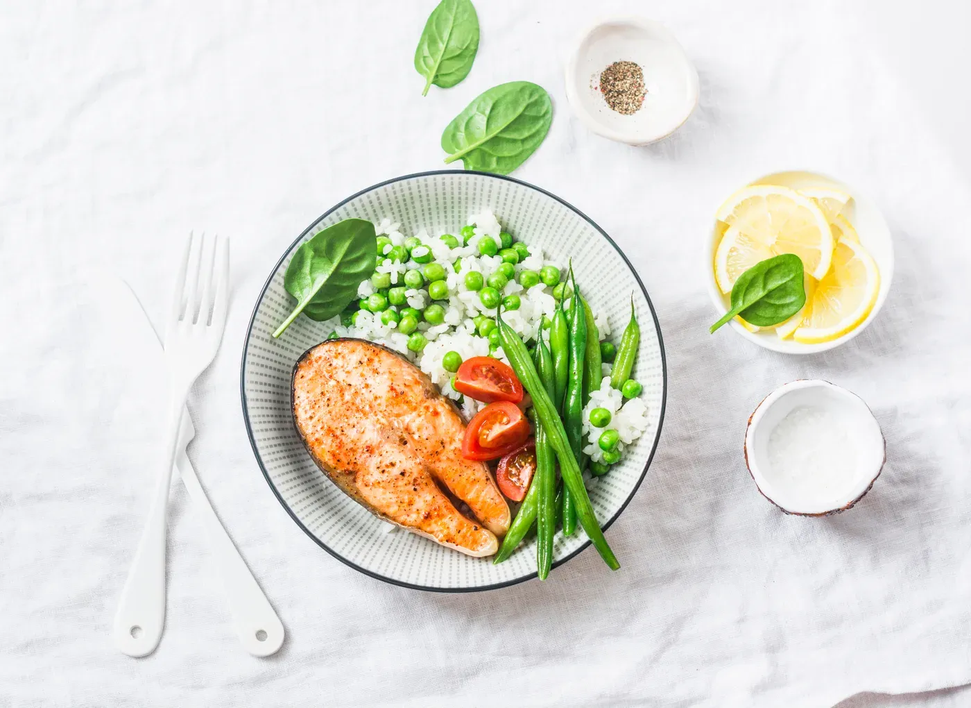 Plate of baked salmon steak with rice, peas, green beans and tomatoes