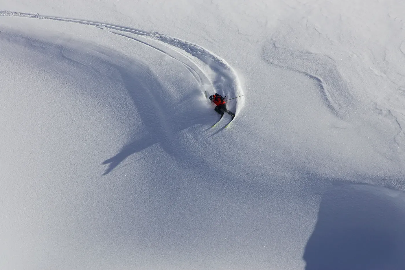 Aerial view of a skier carving a turn on a snowy slope
