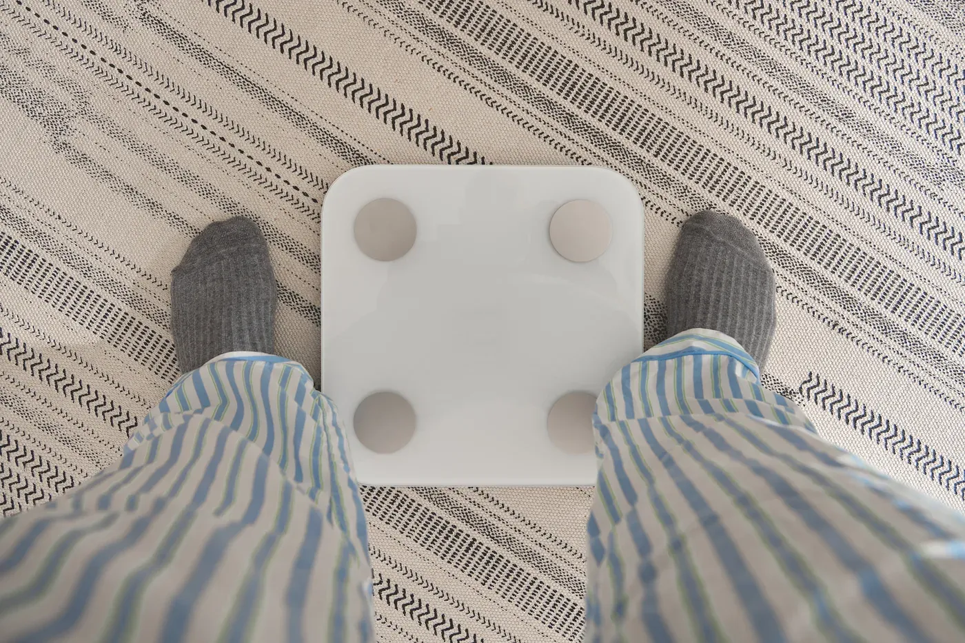Feet in socks and pyjamas beside a white smart bathroom scale