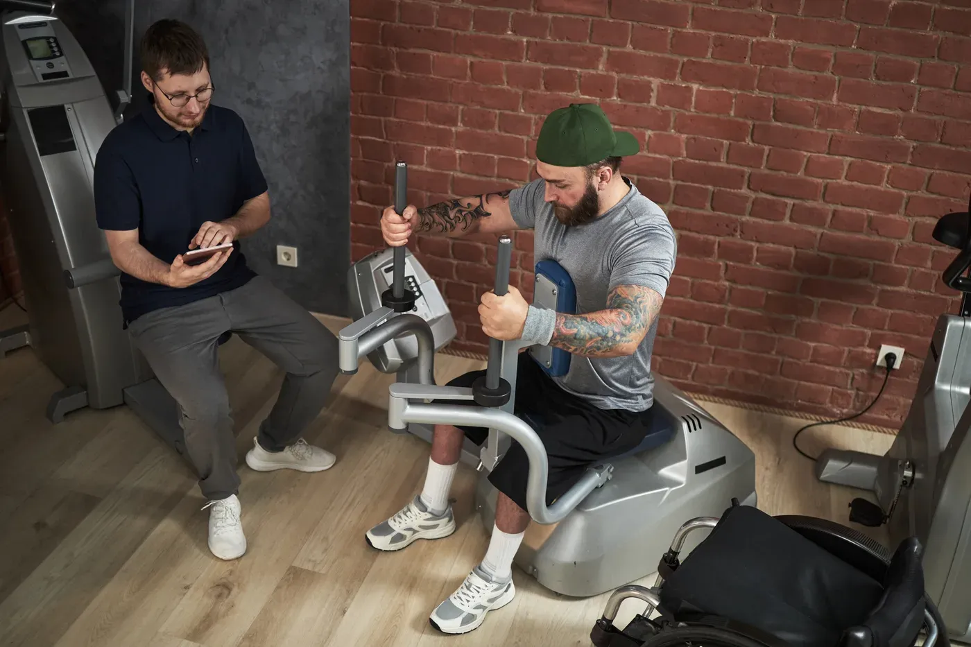 Trainer with a tablet coaching a man on a leg machine in a gym