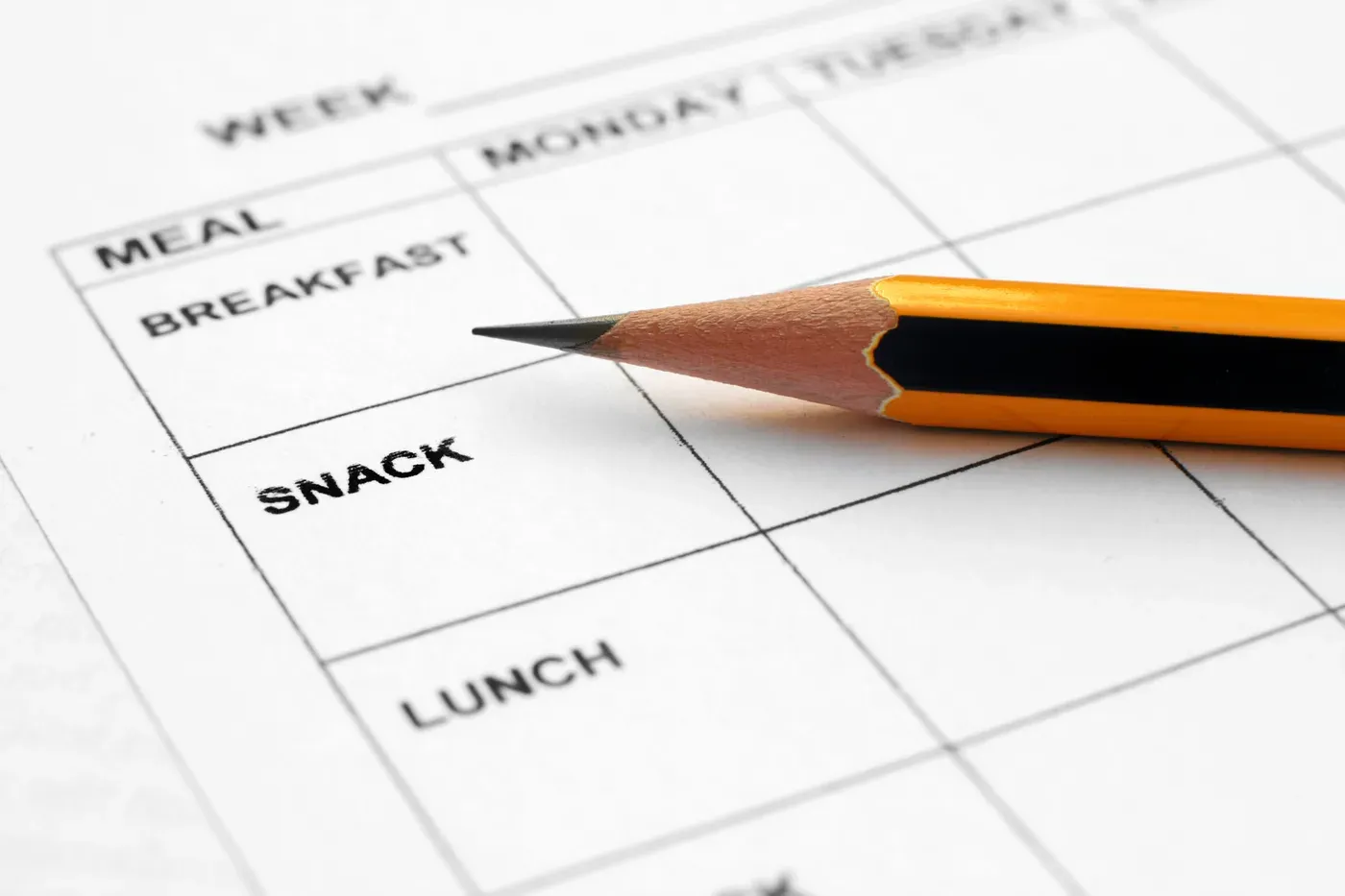 Pencil resting on a blank weekly meal planner sheet